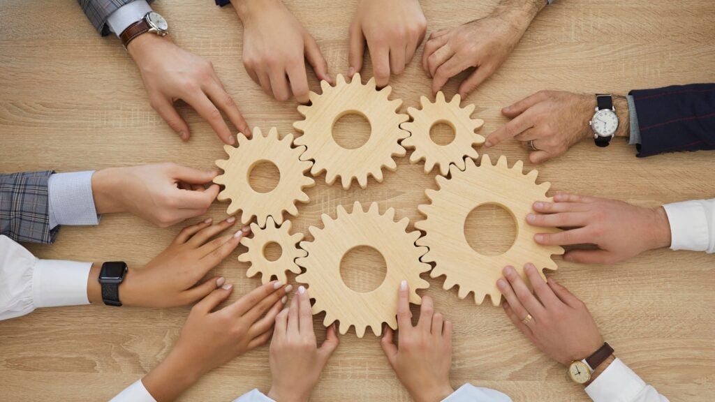 team working together with gears representing different departments impact of M&A success for M&A due diligence blog featured image