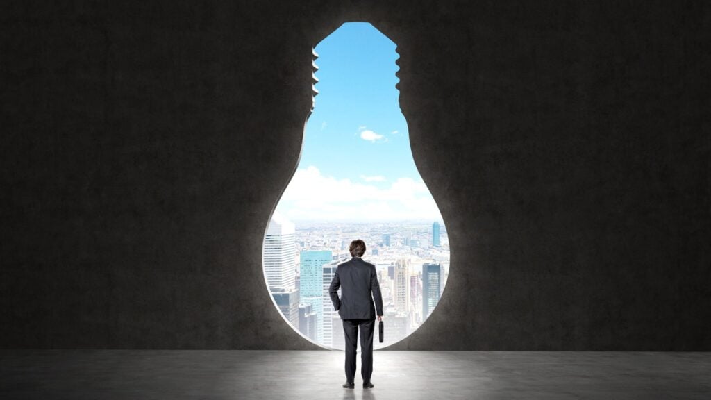 frontier firm image of man standing in front of light bulb cut out looking at the future of business to depict how AI is transforming the future of business